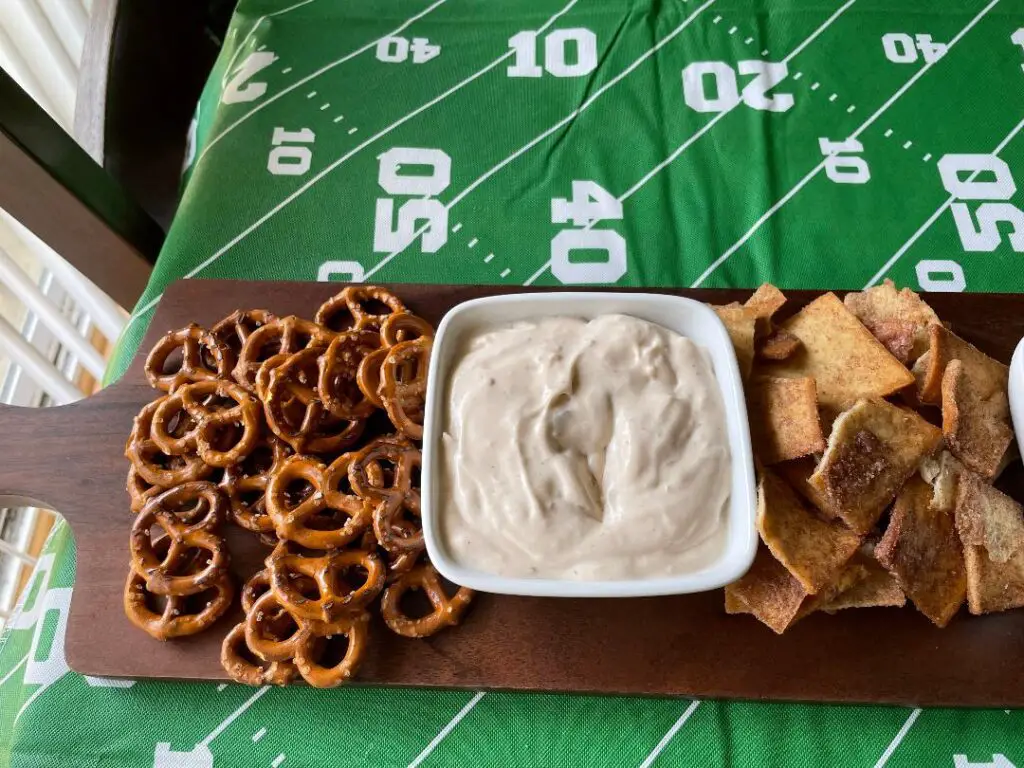  Creamy Caramel Apple Dip served with a variety of snacks such as crackers, and pretzels on a charcuterie board.  