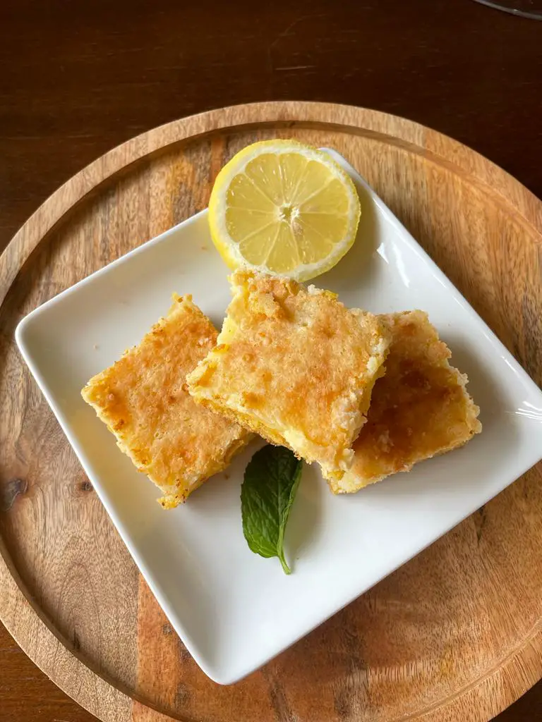 Amazing Lemon Bars Cake decorated with a lemon slice and some mint leaves.