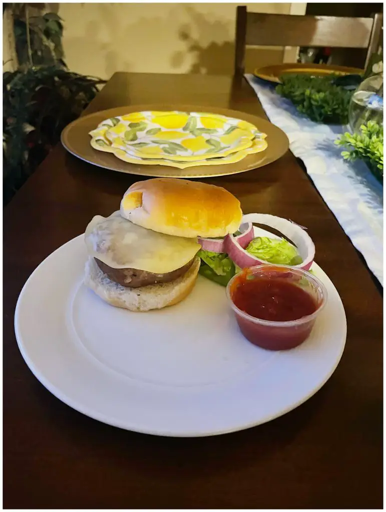 A Ranch Turkey burger dish with onion rings, sliced lettuce and ketchup dip.