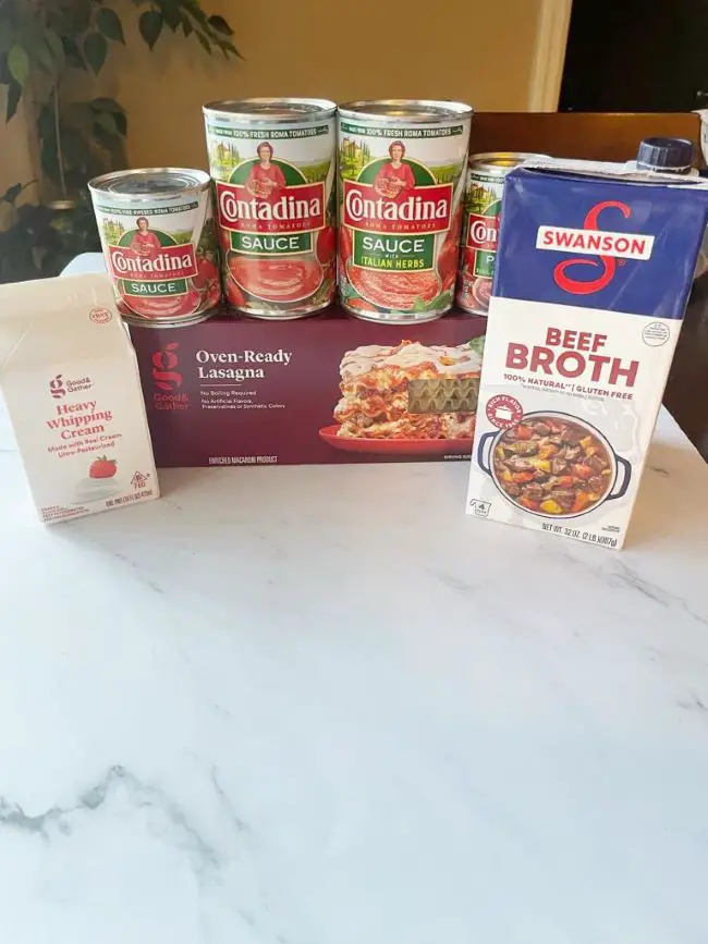 tomato sauce, tomato sauce with Italian herbs, tomato paste, beef broth, whipping cream, and oven-ready lasagna are picture as the ingredients for lasagna soup
